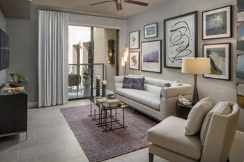 A living room with a white couch, a chair, a coffee table, and a ceiling fan.